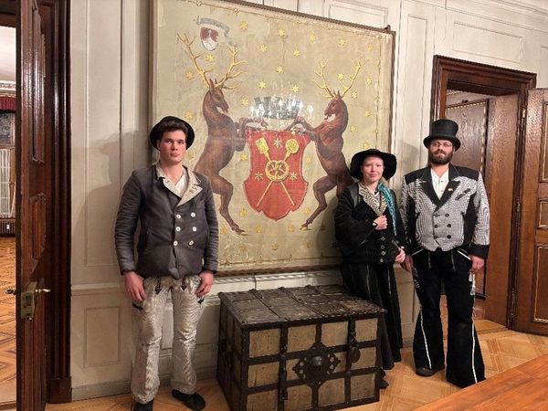 Mitglieder der Zunf zu Pfistern vor ihrem Wappen