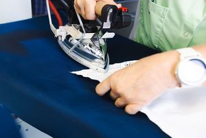 Nahaufname von einem Bügeleisen, welches Hemd bügelt