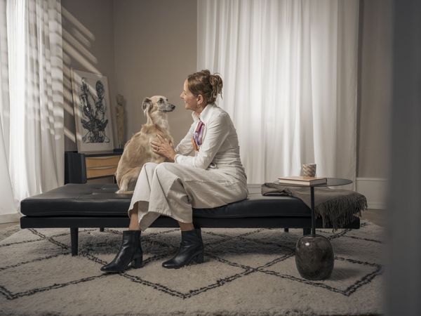 Frau sitzt mit ihrem Hund auf einer Couch